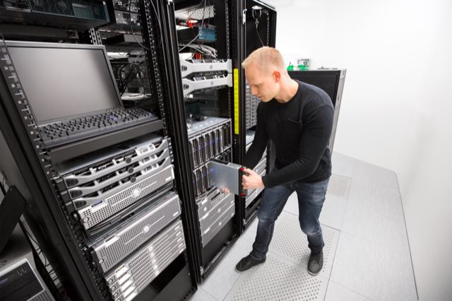 An IT technician installing a blade server into a chassis